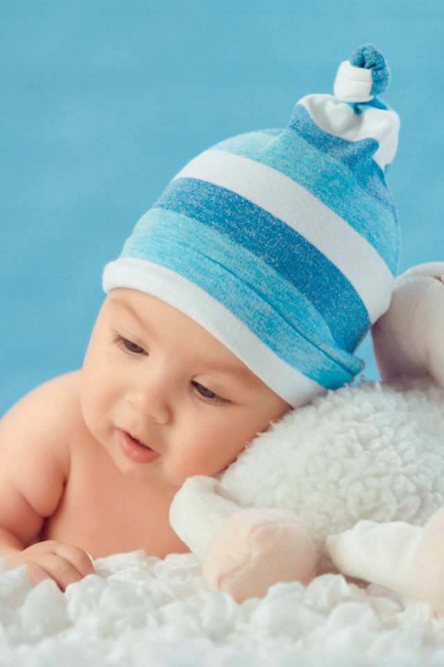 Маленький мальчик в голубой шапке с игрушкой 