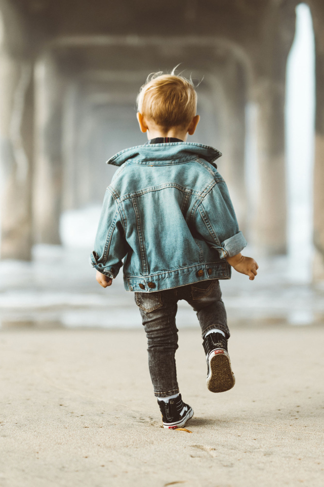 Маленький мальчик в джинсовой куртке спиной
