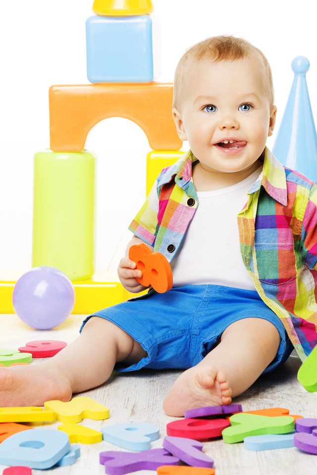 Маленький мальчик играет с разноцветными игрушками 