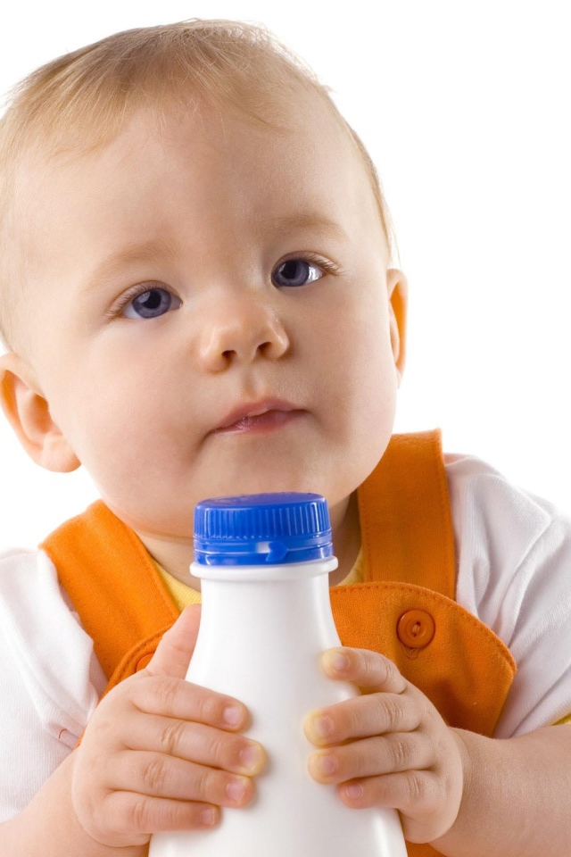 Маленький мальчик с бутылкой молока на белом фоне