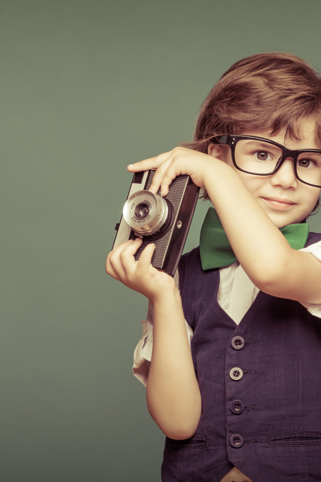 Маленький мальчик в очках с фотоаппаратом