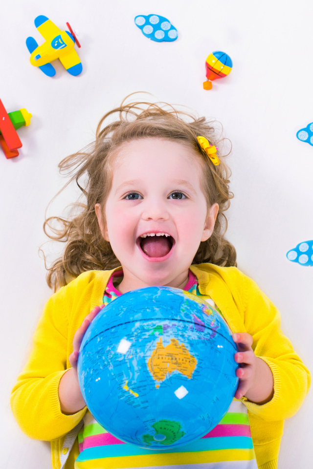 Маленькая веселая девочка с глобусом в руках 
