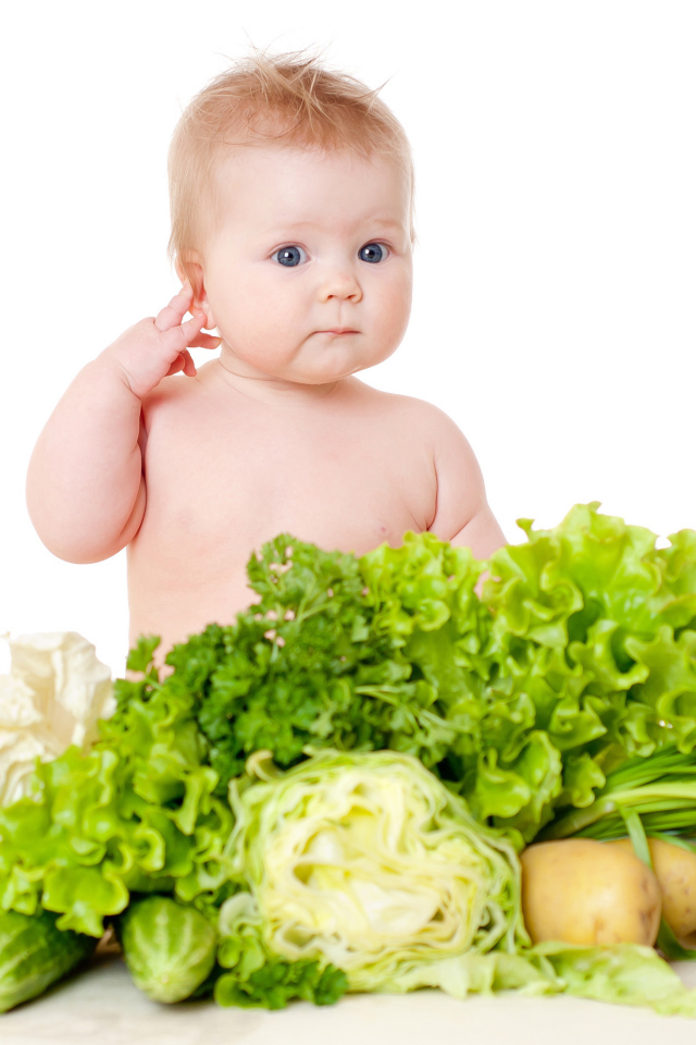 Маленький ребенок с овощами и зеленью на белом фоне
