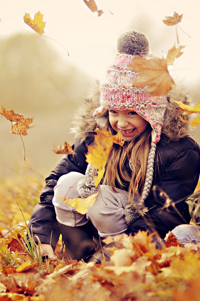 Маленькие дети играют на опавшей желтой листве осенью