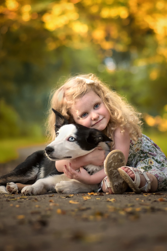 Маленькая милая девочка обнимает на дороге собаку