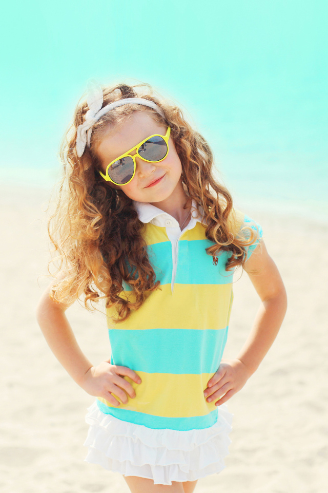 Маленькая модная девочка в солнечных очках на пляже