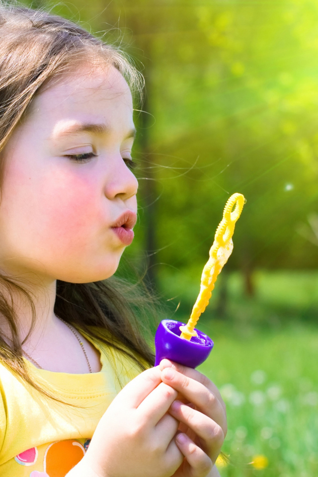 Маленькая девочка пускает мыльные пузыри