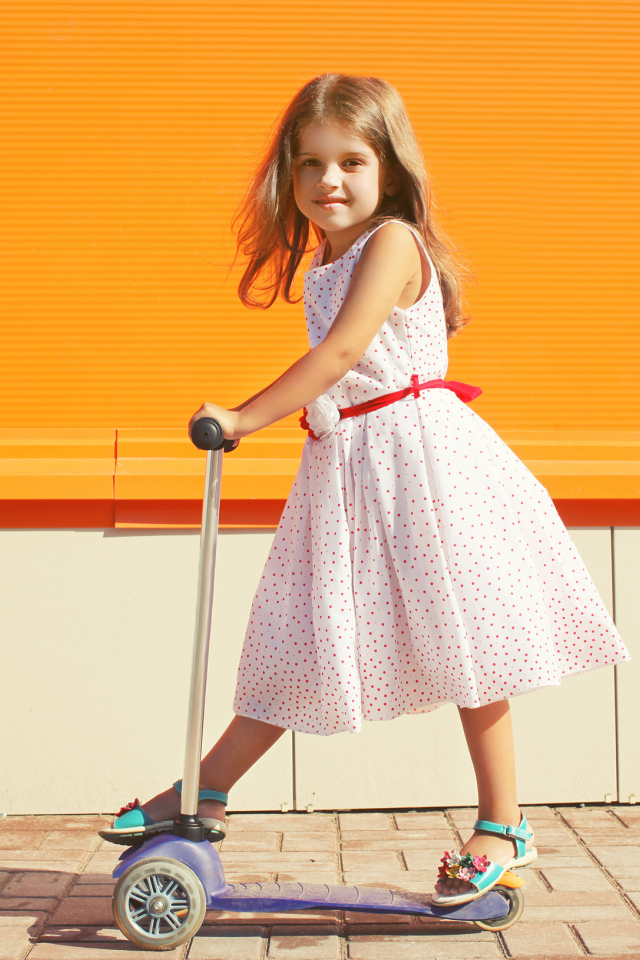 Маленькая девочка в платье на самокате 