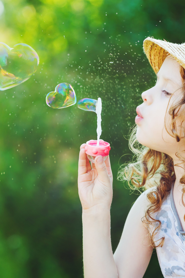 Маленькая девочка в шляпе с мыльными пузырями