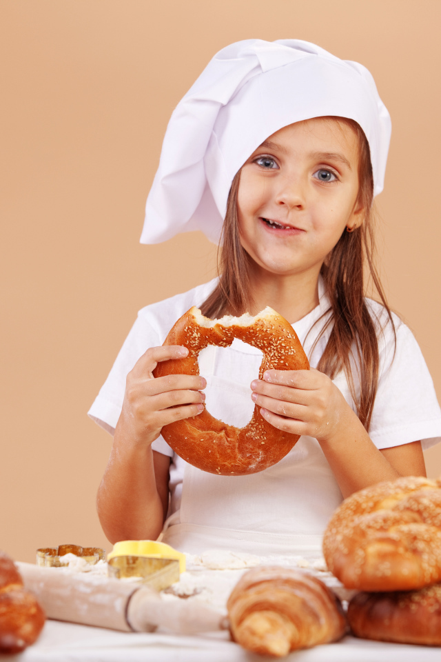Маленькая девочка в костюме повара и свежей выпечкой