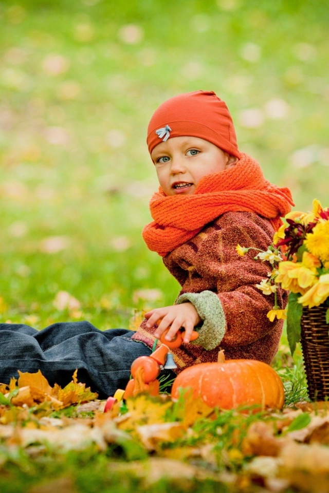 Маленькая девочка сидит на траве с корзиной цветов осенью