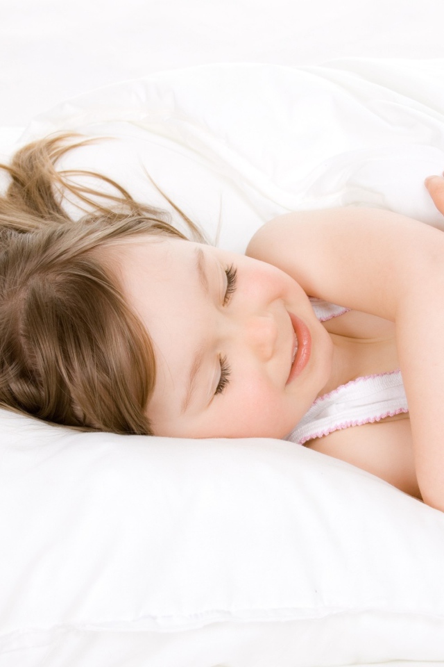 Маленькая девочка спит на белой кровати