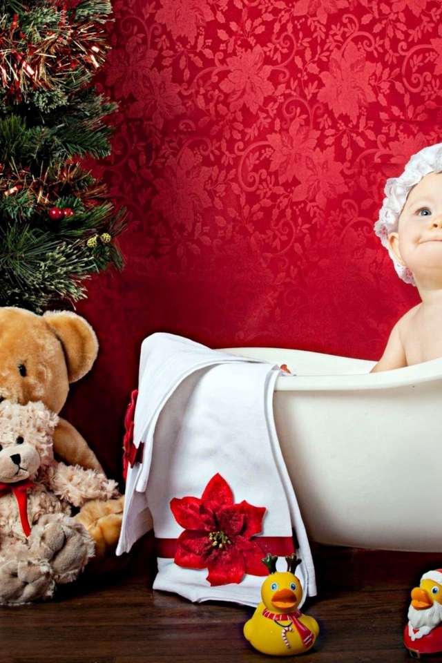 Маленькая девочка сидит в белой ванне у елки с игрушками