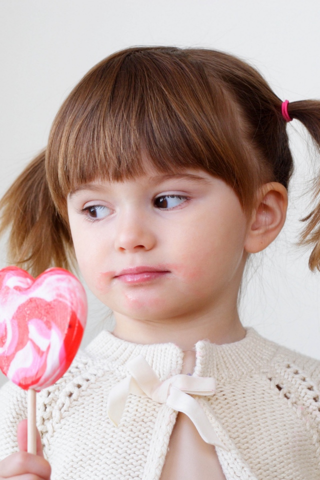 Маленькая девочка с большой конфетой на палочке