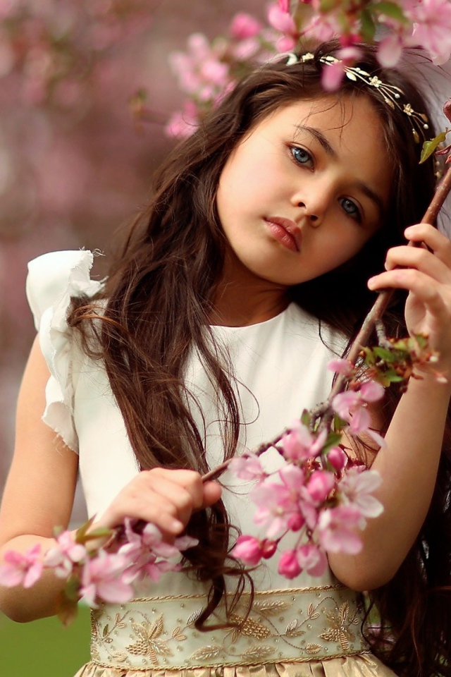 Маленькая девочка у цветущей розовыми цветами ветки