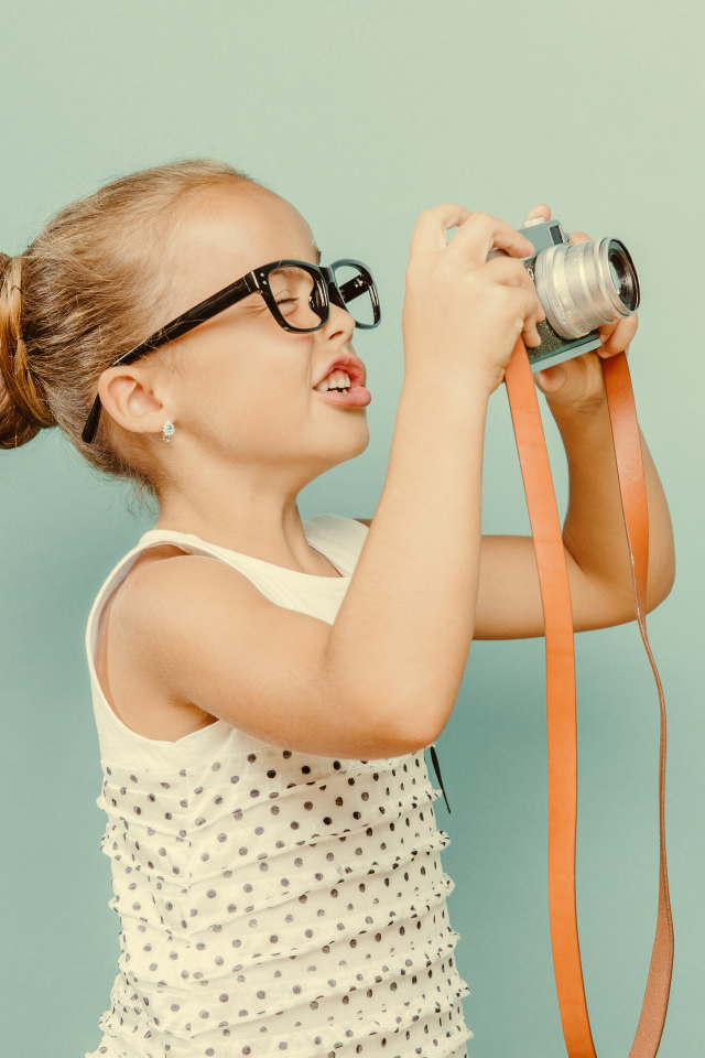 Маленькая девочка в очках с фотоаппаратом