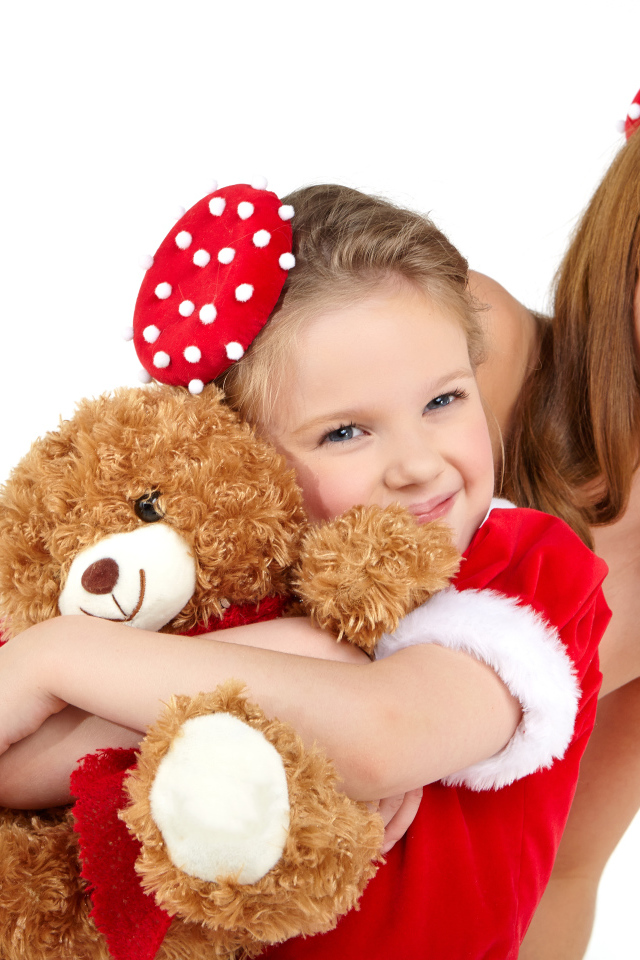 Маленькая девочка с мамой обнимает игрушечного медвежонка