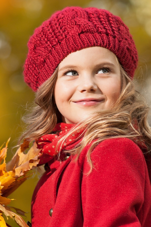 Маленькая девочка с желтыми листьями в руке осенью