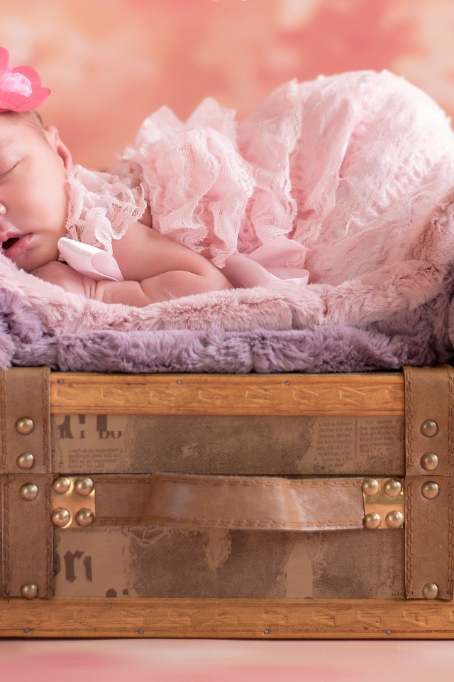Маленькая новорожденная девочка спит на чемодане