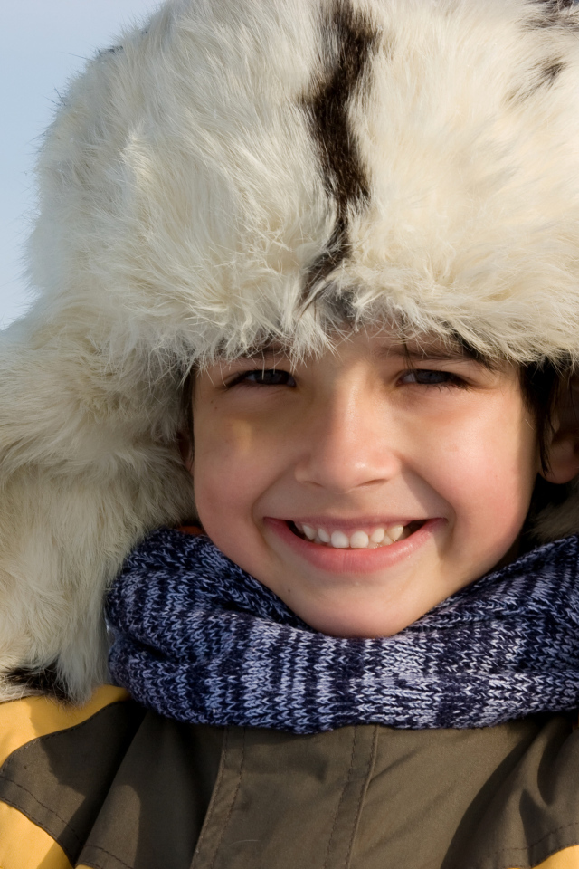 Маленький улыбающийся мальчик в теплой шапке зимой