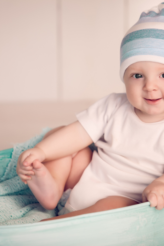 Маленький улыбающийся ребенок сидит в железном тазике