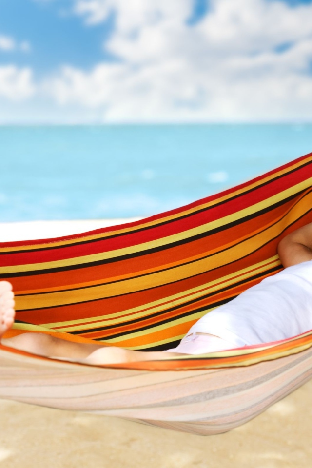 Маленькая улыбающаяся девочка в гамаке на пляже