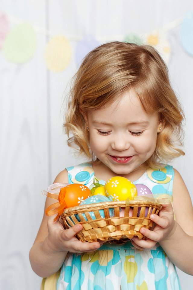 Маленькая улыбающаяся девочка с пасхальными яйцами в руках