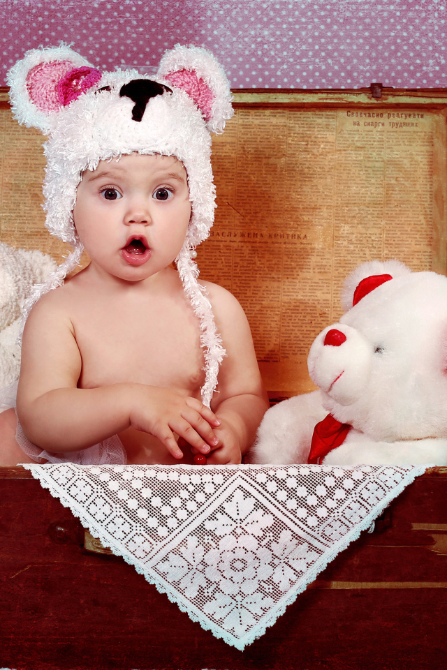 Маленький удивленный ребенок сидит в чемодане с игрушками