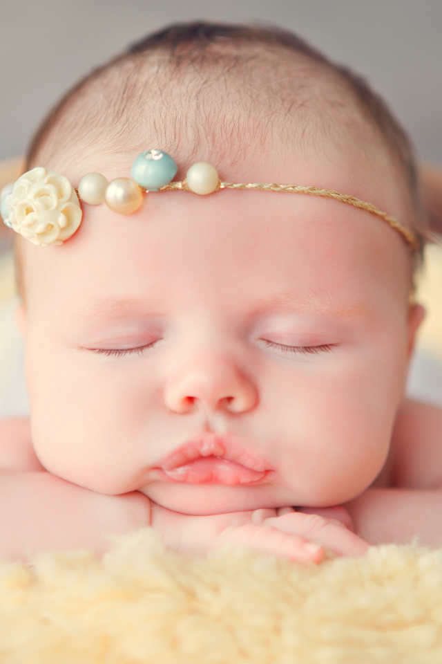 Спящая грудная девочка с красивым украшением на голове