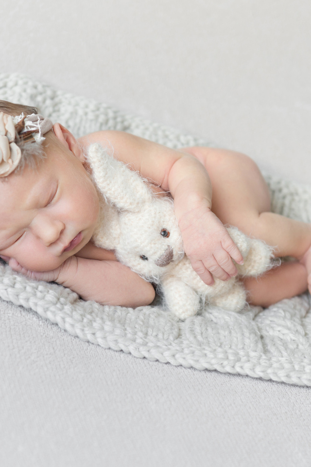 Спящий грудной ребенок с вязаной игрушкой