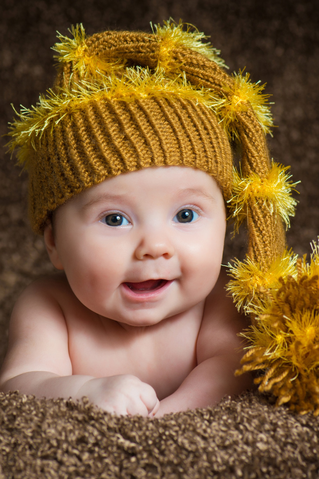 Улыбающийся малыш в красивой вязанной шапке 