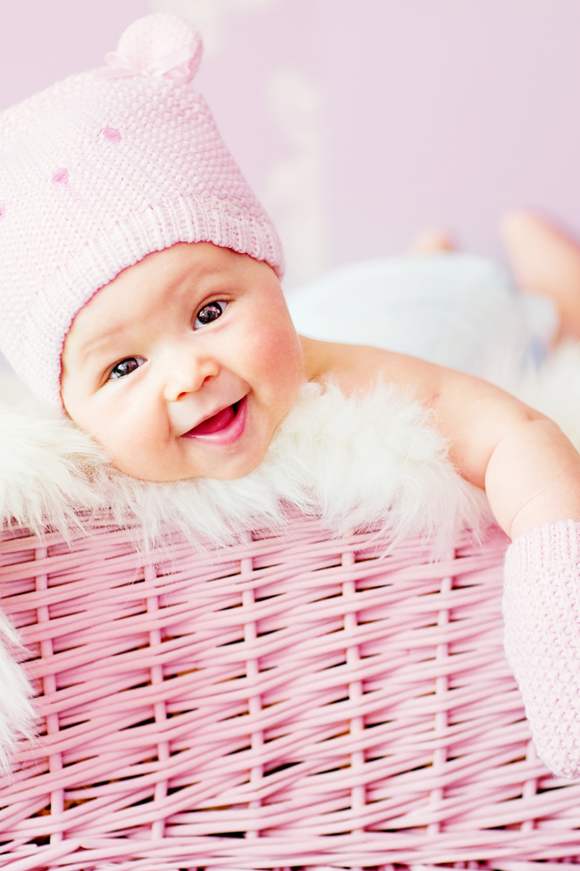 Улыбающийся грудной ребенок лежит в розовой корзине