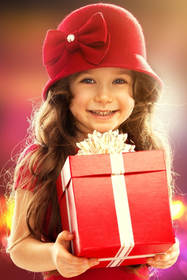 Улыбающаяся голубоглазая девочка с большим подарком в руках
