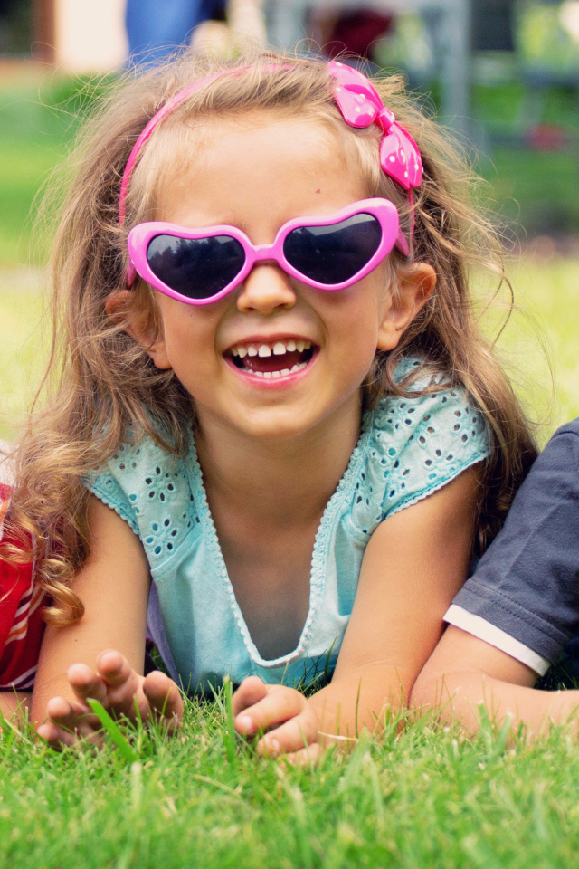 Улыбающиеся мальчики и девочка лежат на зеленой траве