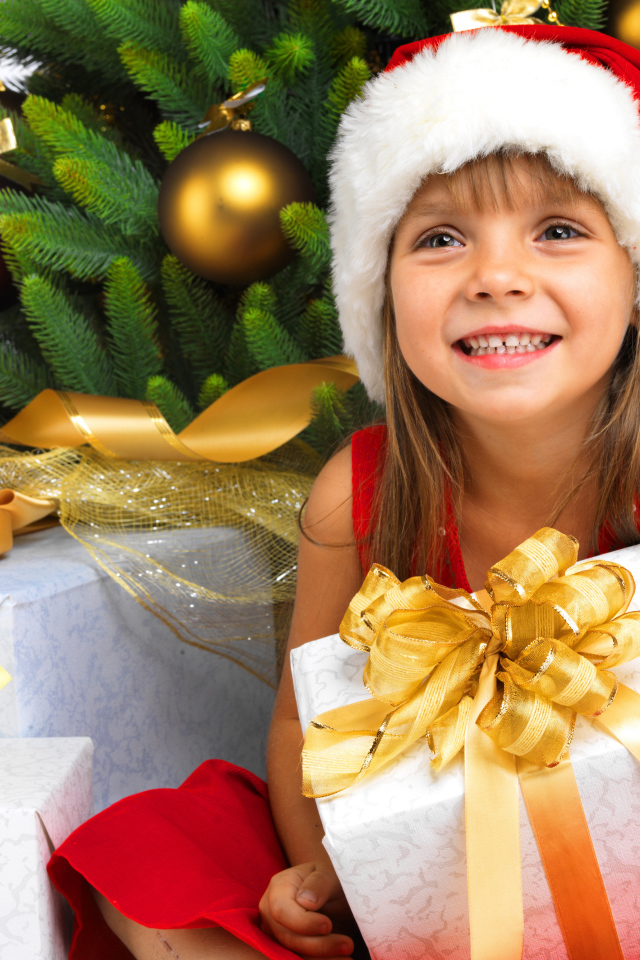 Улыбающаяся девочка в новогоднем костюме с подарками под елкой