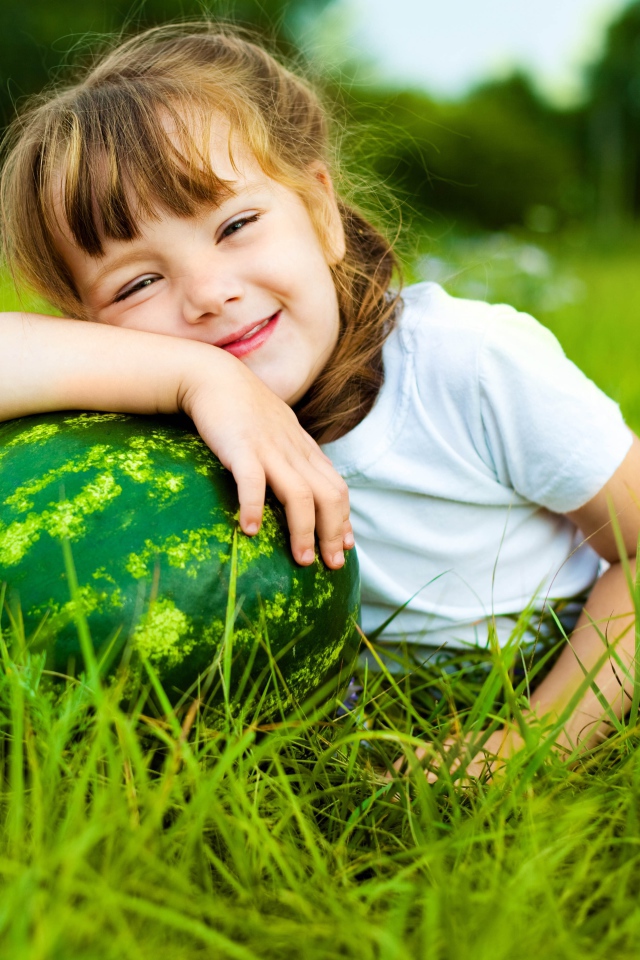 Улыбающаяся девочка с зеленым арбузом на траве