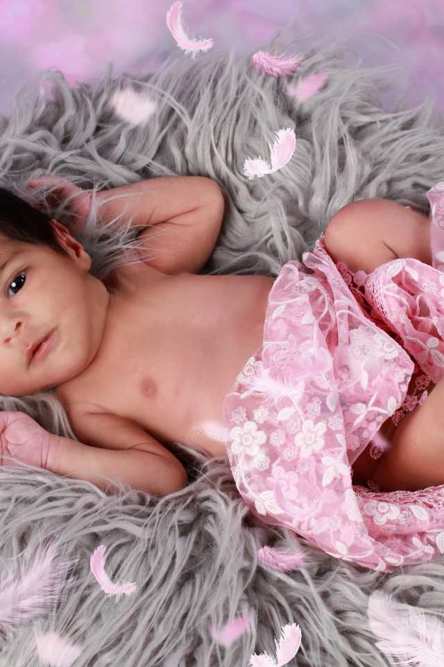 Младенец лежит на сером меховом покрывале 