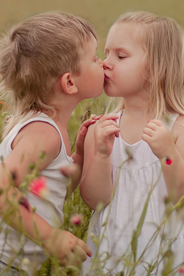 Первый поцелуй мальчика и девочки на цветущем поле
