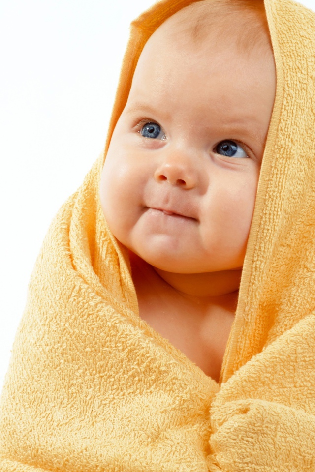 Грудной ребенок в желтом полотенце на белом фоне