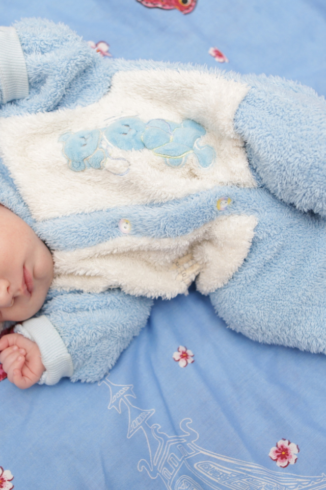 Грудной спящий ребенок в голубом костюме