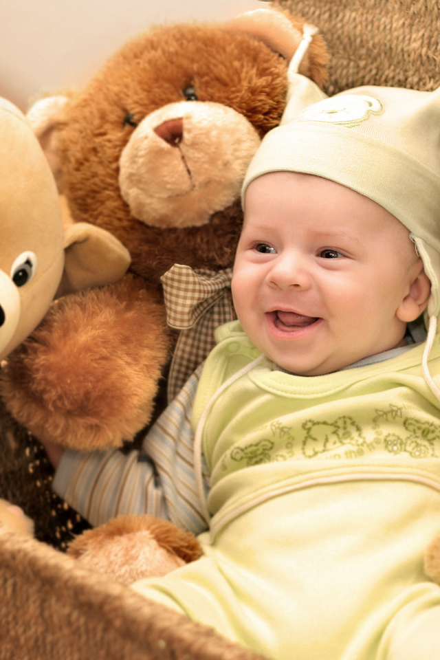 Грудной улыбающийся ребенок в корзине с игрушками