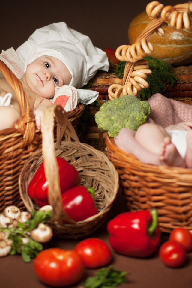 Два младенца в шапках повара лежат в корзинах с продуктами
