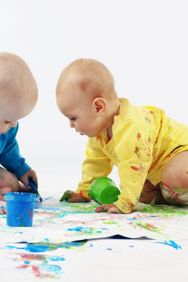 Два малыша рисуют красками на белом фоне