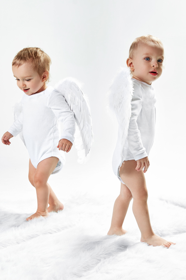 Два маленьких мальчика в костюмах ангела на белом фоне