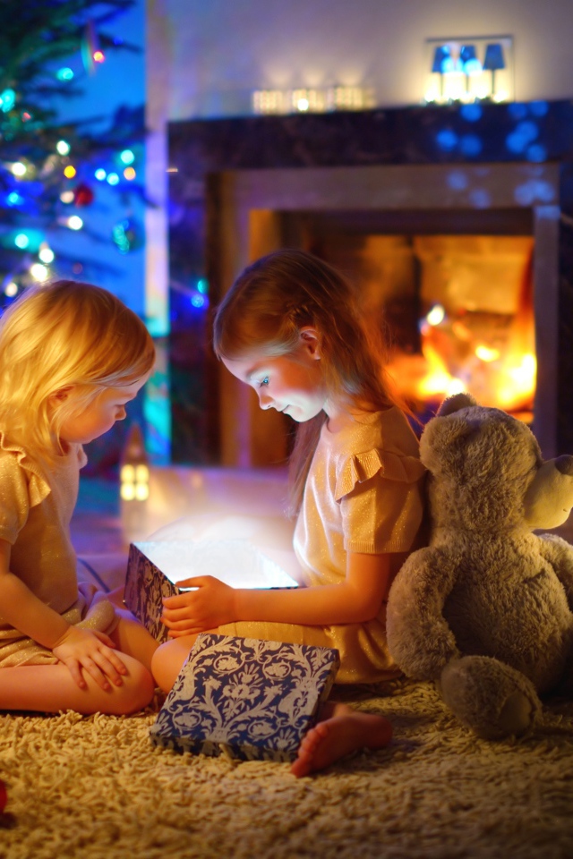 Две маленькие девочки с игрушками у камина
