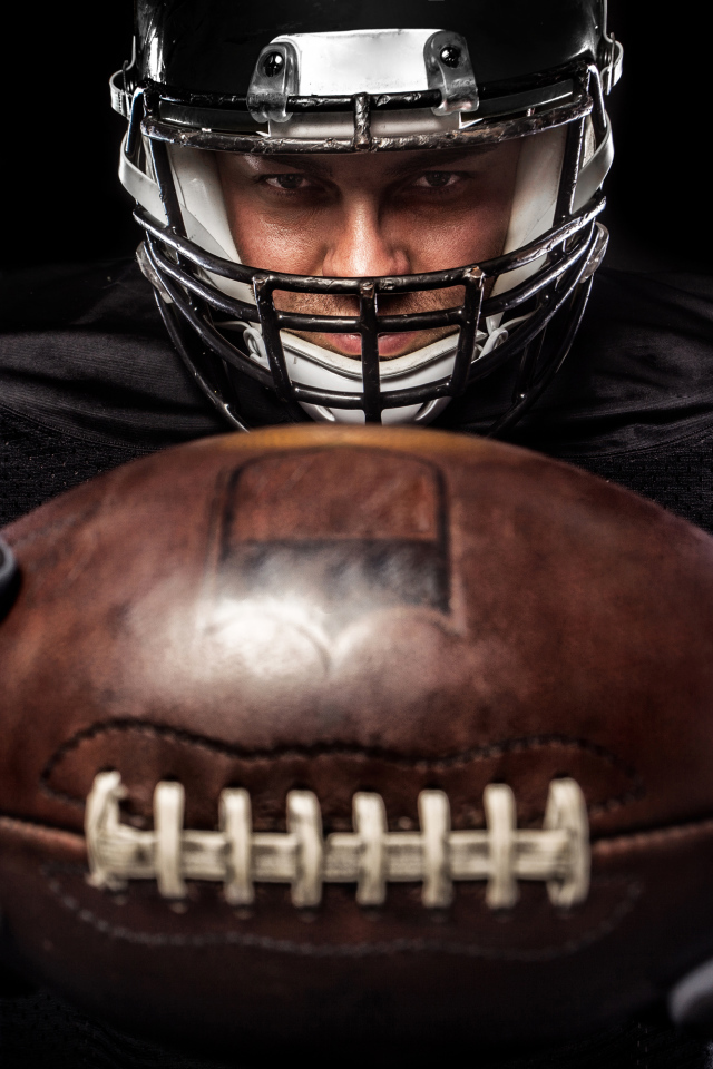 American football player with ball on black background