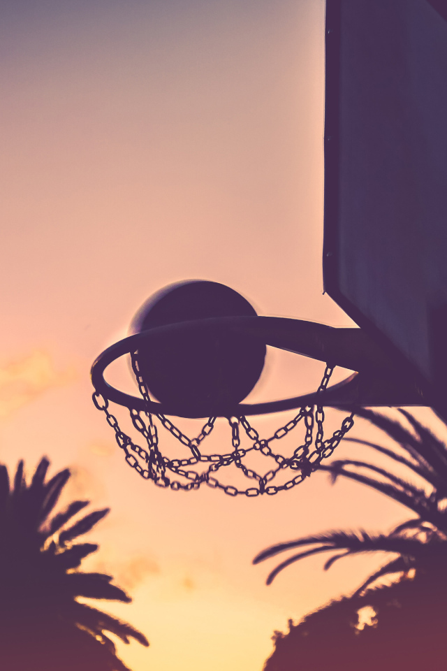 Баскетбольное кольцо с мячом на закате