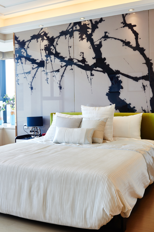 Красивая светлая спальня с большой кроватью и рисунком на стене 