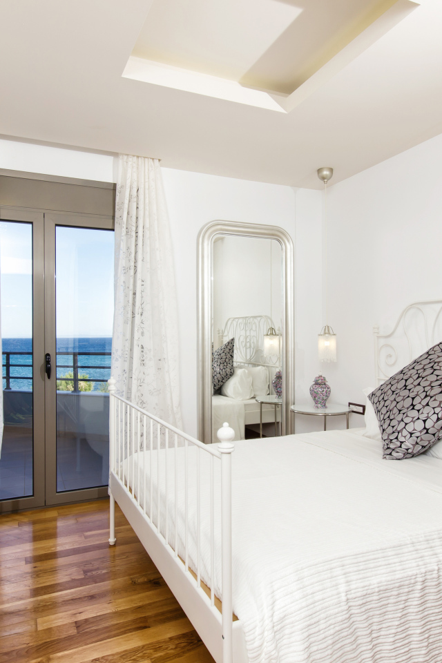 Светлая спальня с большой белой кроватью и телевизором 