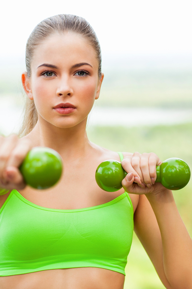 Молодая спортивная блондинка с гантелями в руках